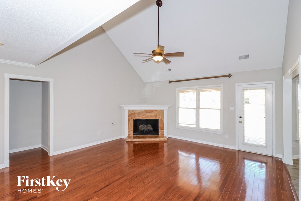 an empty living room with a fireplace and a ceiling fan