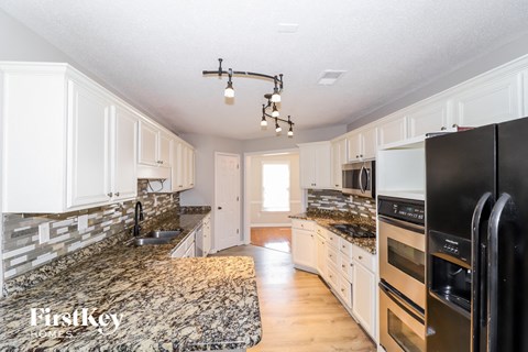 a white kitchen with granite counter tops and black appliances