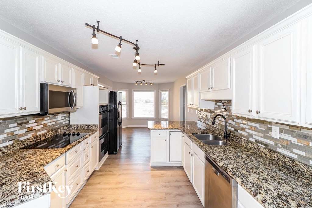 a kitchen with white cabinets and granite counter tops and a sink