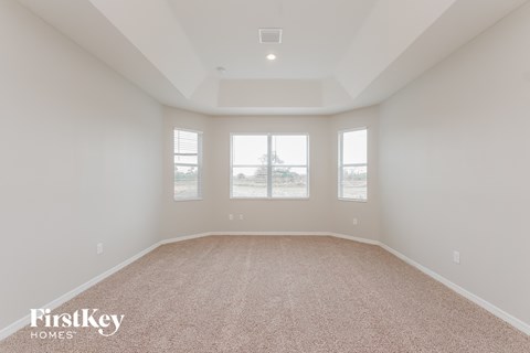 a living room with a carpet and three windows
