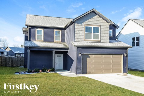 A house with a garage and a driveway in front of it.