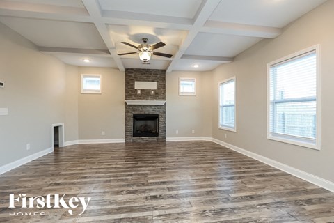A spacious room with a fireplace and wood flooring.