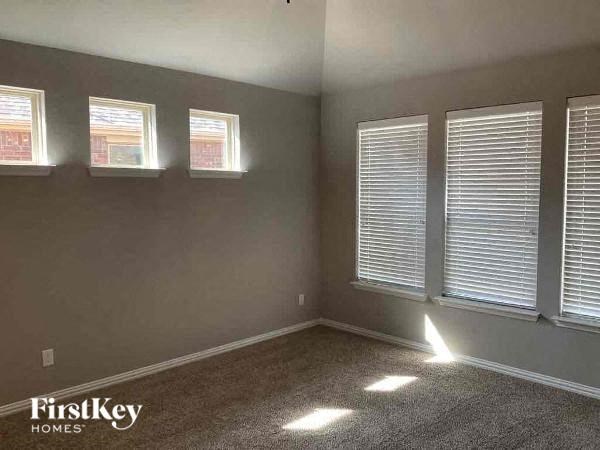 an empty room with three windows and a carpet