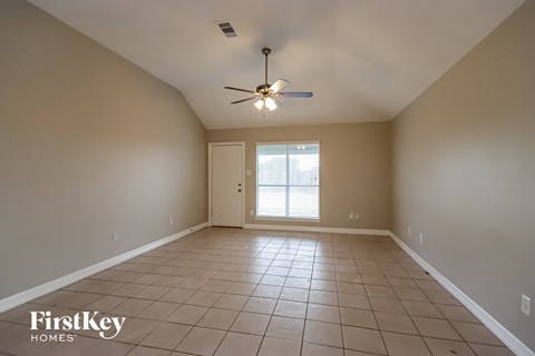 A spacious room with a ceiling fan and tiled floor.