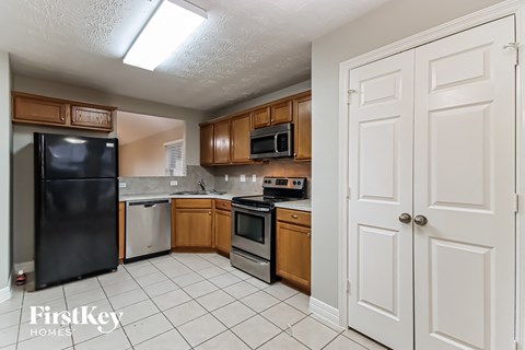 A kitchen with a black fridge and wooden cabinets.
