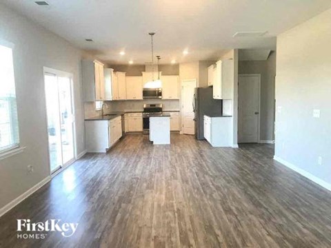 A spacious kitchen with wooden floors and white cabinets.
