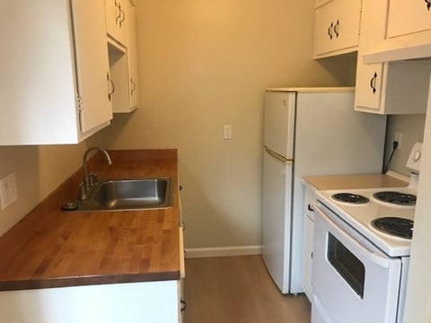A kitchen with white appliances and wooden countertops.