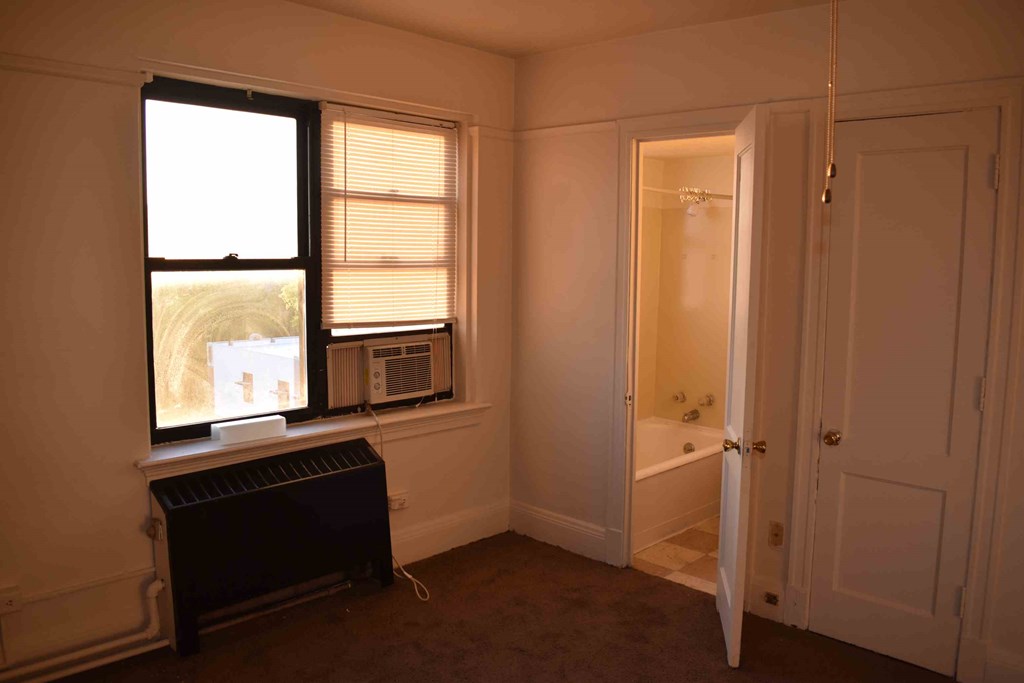 a small room with a window and a radiator and a sink
