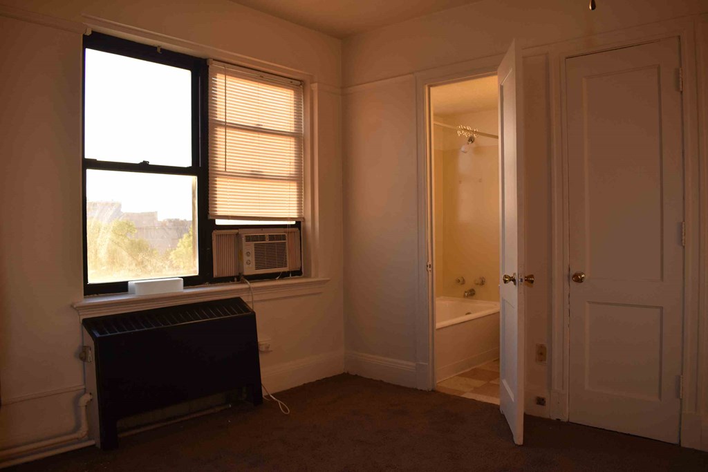 a small room with a radiator and a window and a bath tub