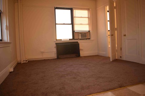 an empty living room with a microwave and a window