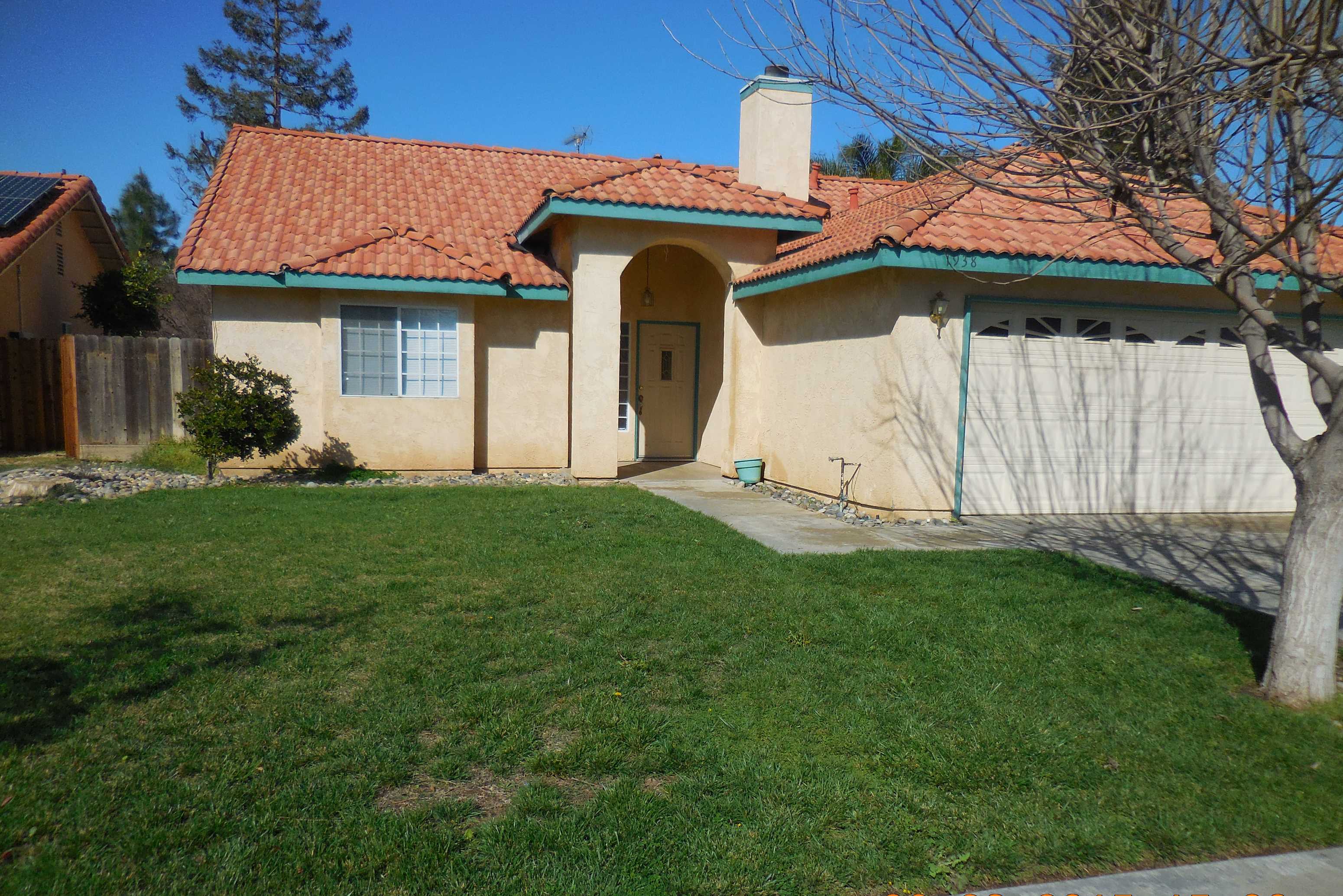 the front of a house with a lawn and a tree