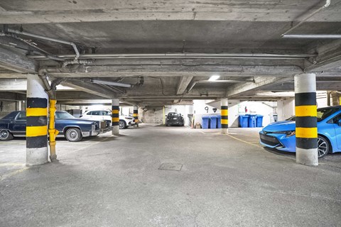 A parking garage with a blue car parked in the foreground.