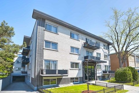 A modern apartment building with a black fence in front.