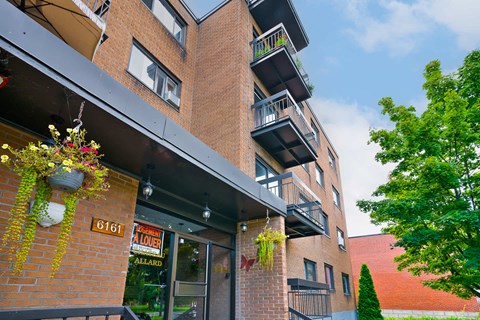 A red brick building with a balcony and a sign that says 6161.