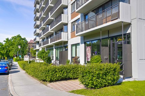 A modern apartment building with a blue car parked on the street.