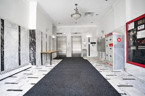 A hallway with a black carpet and marble walls.