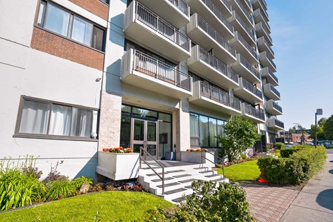A modern apartment building with a well-maintained garden in front.