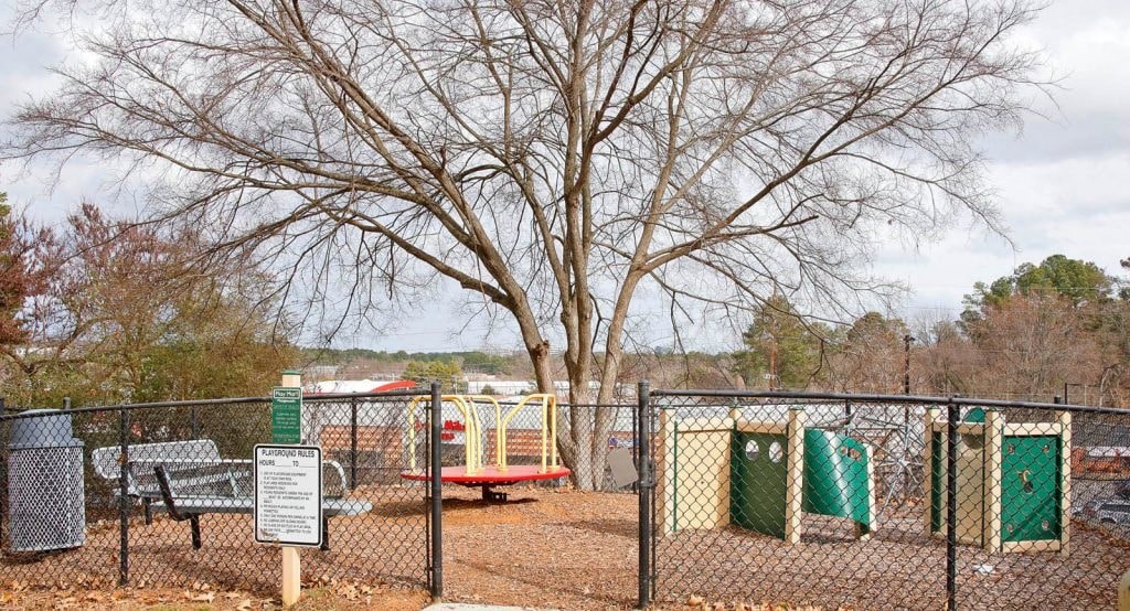 a playground with a tree and a fence