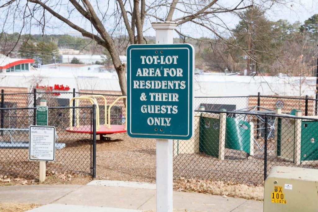 a sign is posted on a pole in front of a playground