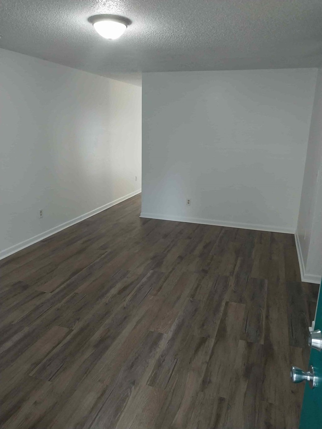 an empty living room with wooden floors and white walls