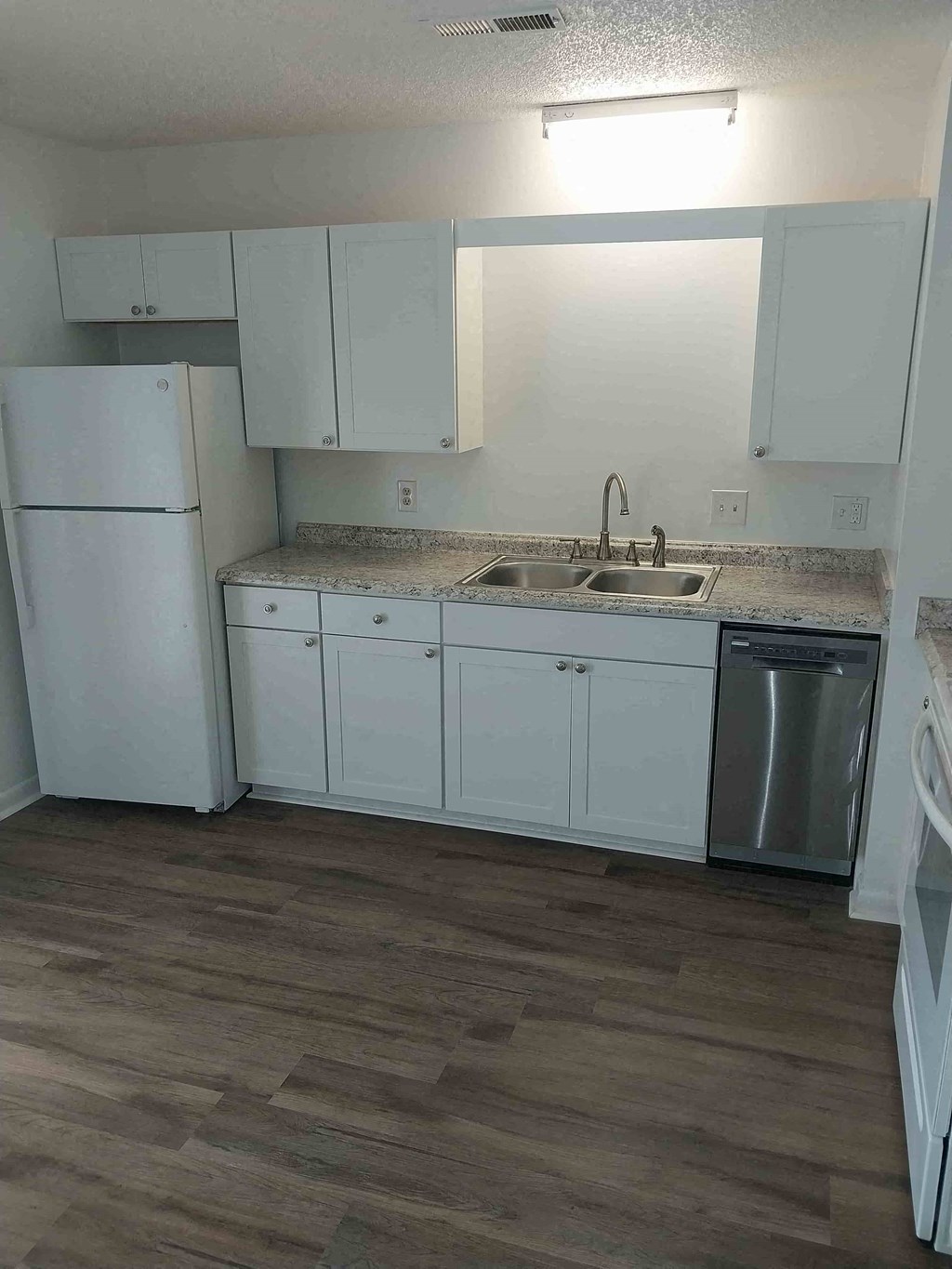 a kitchen with white cabinets and a sink and a refrigerator