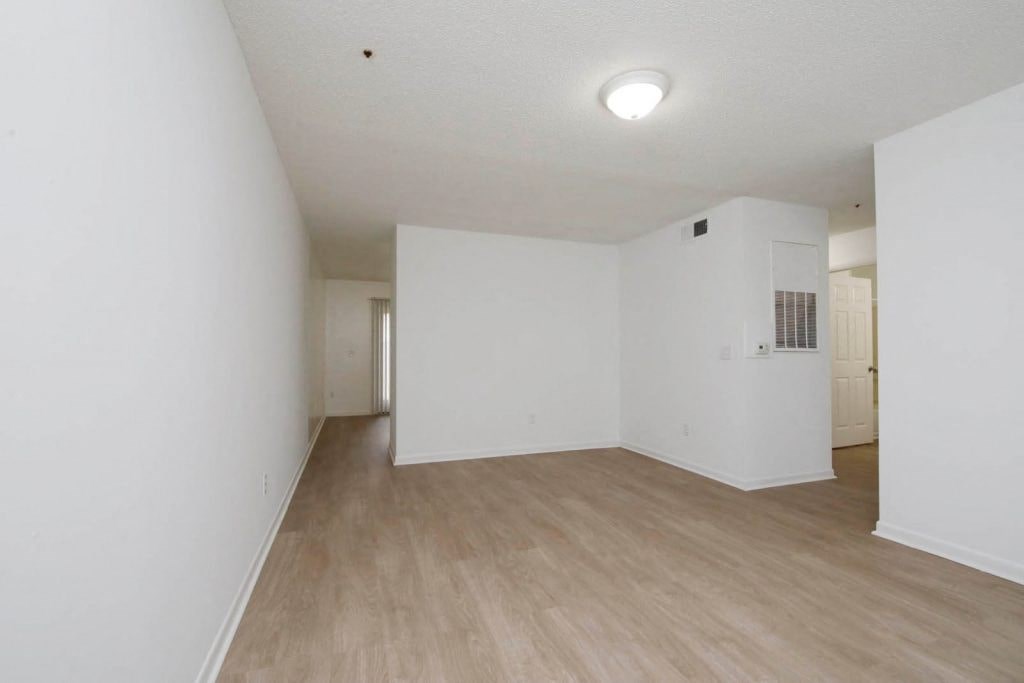 an empty living room with white walls and wood floors
