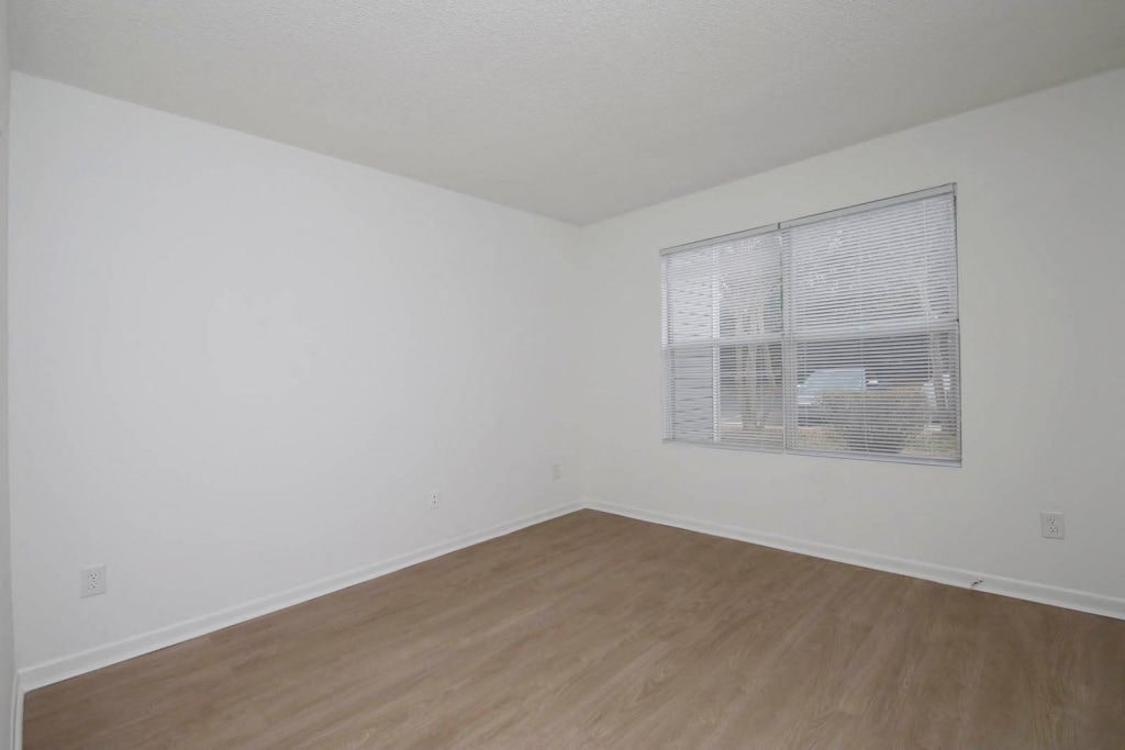 an empty room with a window and wooden floors