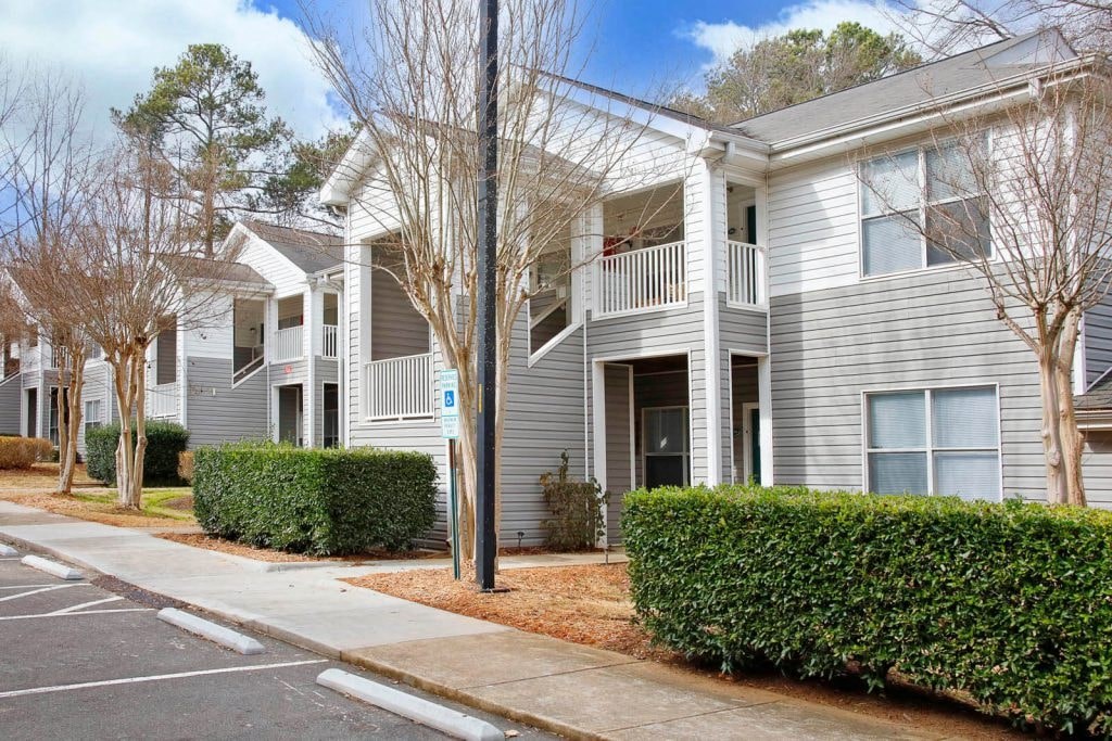 a white apartment building with a sidewalk in front of it
