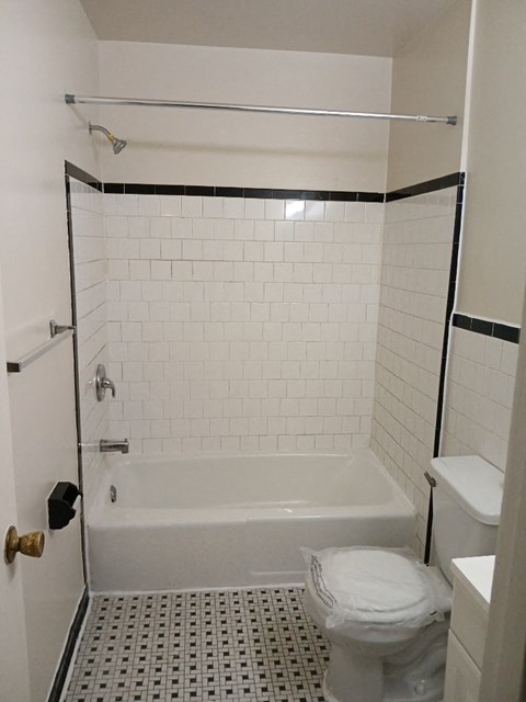 A white toilet sits in a bathroom with a white tub and a shower.