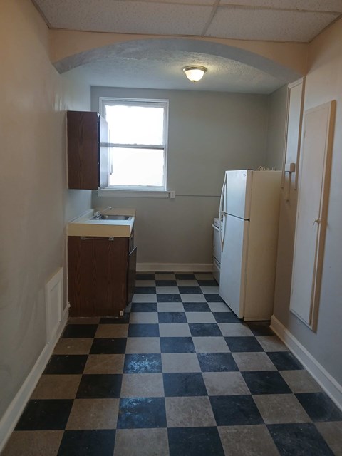 A kitchen with a checkered floor and a window.