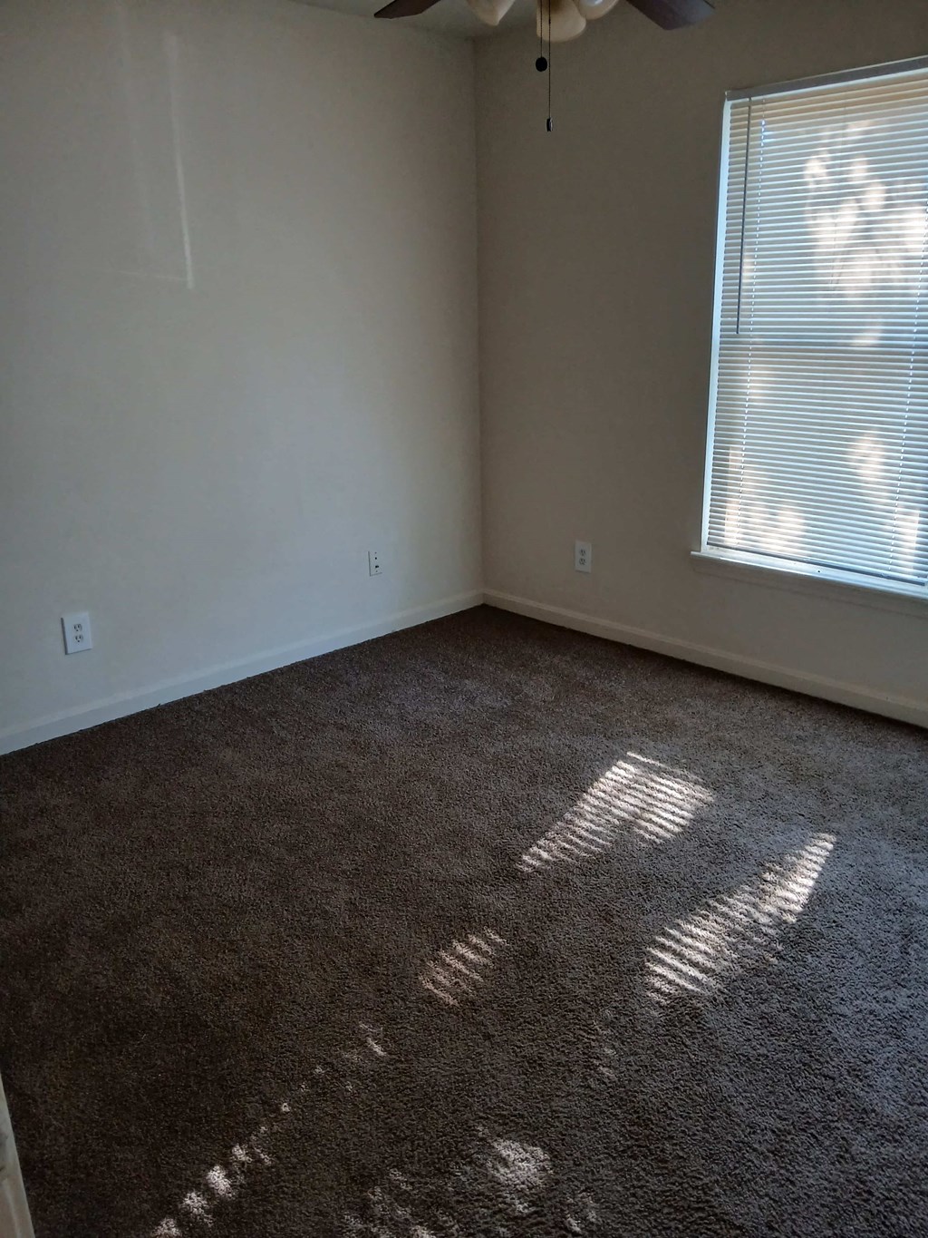 an empty room with a carpeted floor and a window