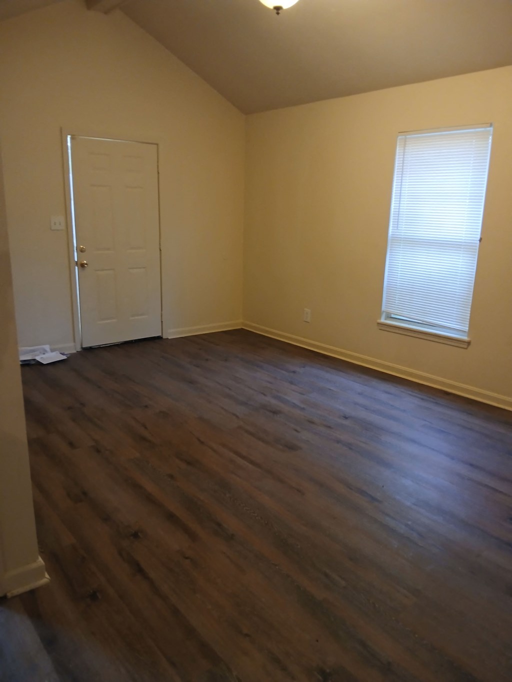 an empty living room with wooden floors and a white door