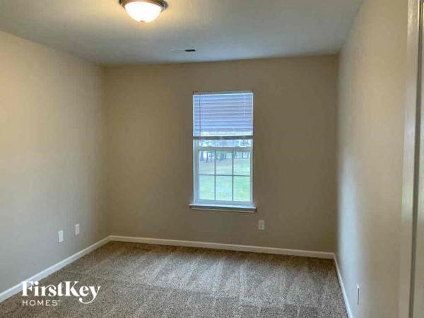an empty bedroom with a window and a carpeted floor