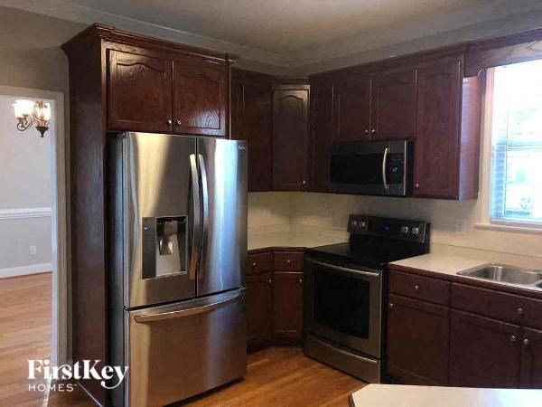 A kitchen with wooden cabinets and a stainless steel refrigerator.