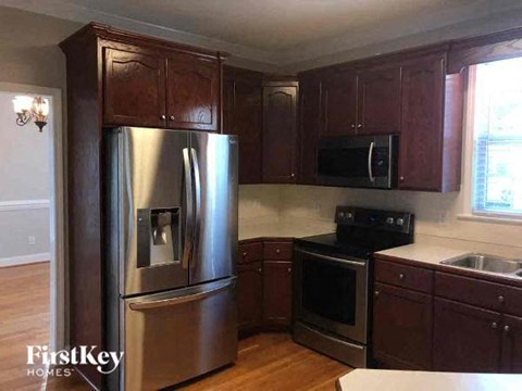 A kitchen with wooden cabinets and a stainless steel refrigerator.