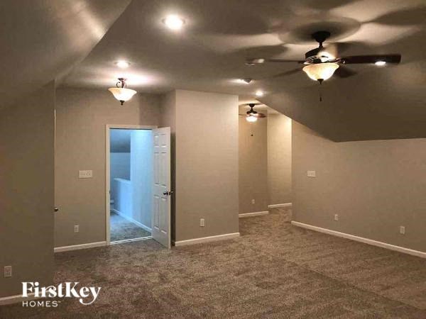 A room with a carpet floor and a ceiling fan.