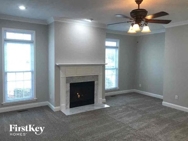 A living room with a fireplace and a ceiling fan.