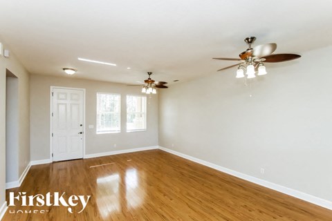 A spacious room with a ceiling fan and wooden flooring.