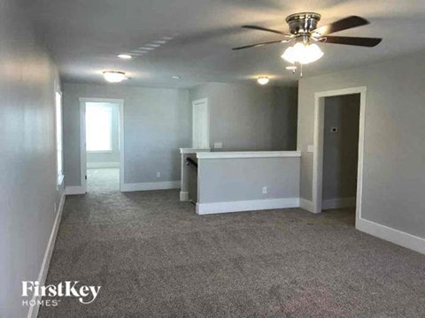 A spacious room with a ceiling fan and carpeted floor.