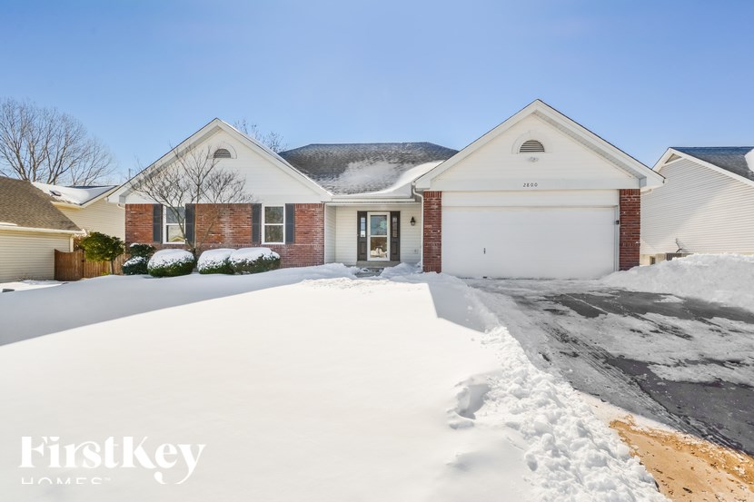 A house with a snow-covered driveway in front of it.
