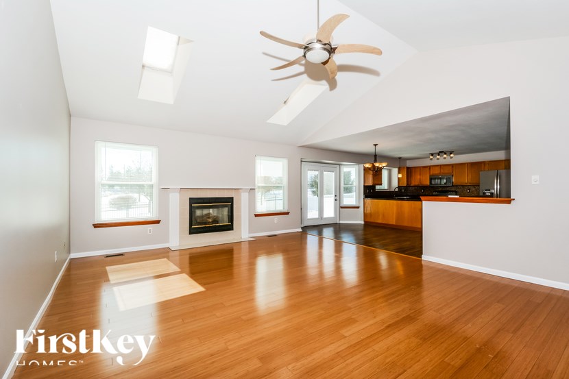 A spacious living room with a fireplace and a ceiling fan.