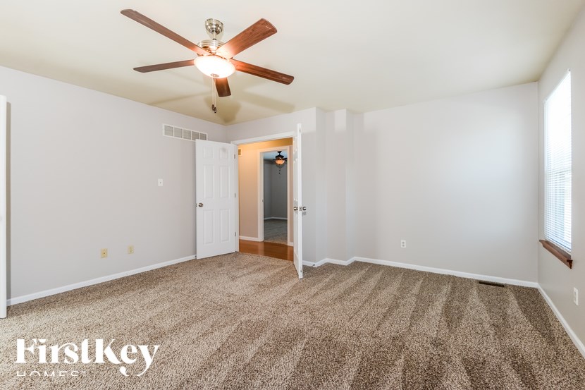 A room with a ceiling fan and carpeted floor.