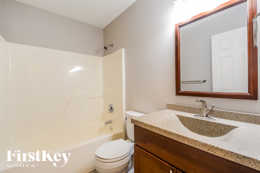A bathroom with a toilet, sink, and mirror.