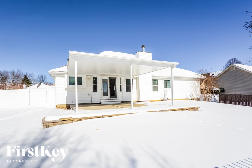 A white house with a porch and a snowy landscape in the foreground.