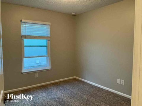 an empty room with a window and a carpet