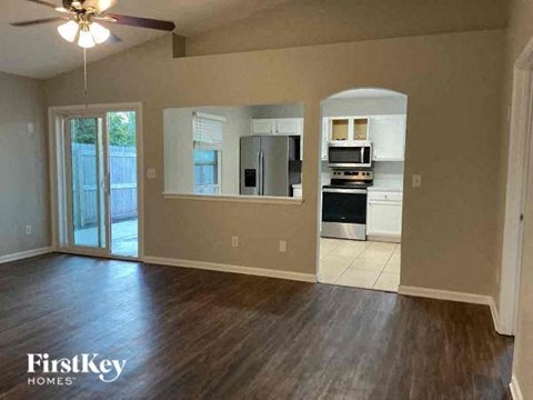 an empty living room and kitchen with a wood floor