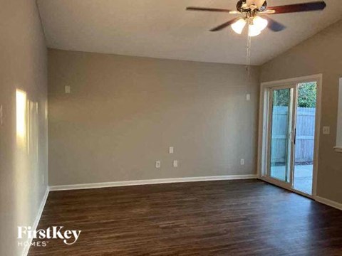 a empty living room with a ceiling fan and a sliding glass door