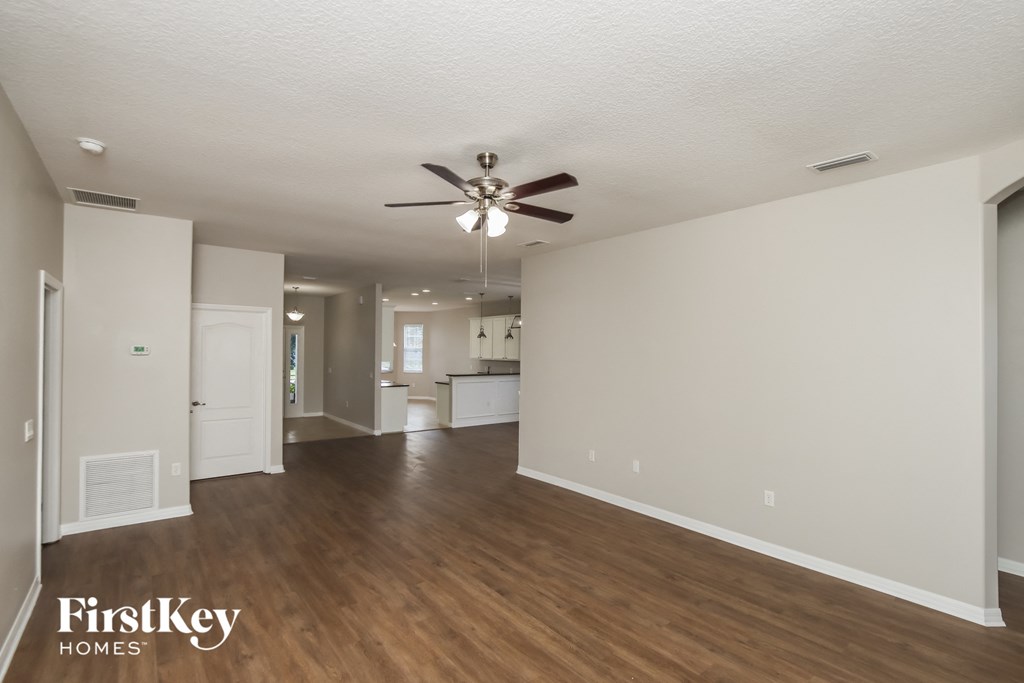 an empty living room with a ceiling fan and wood flooring