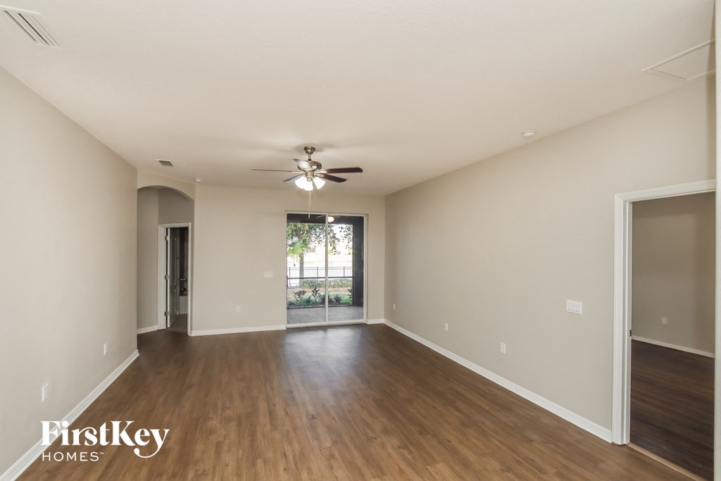 an empty living room with wood flooring and a ceiling fan