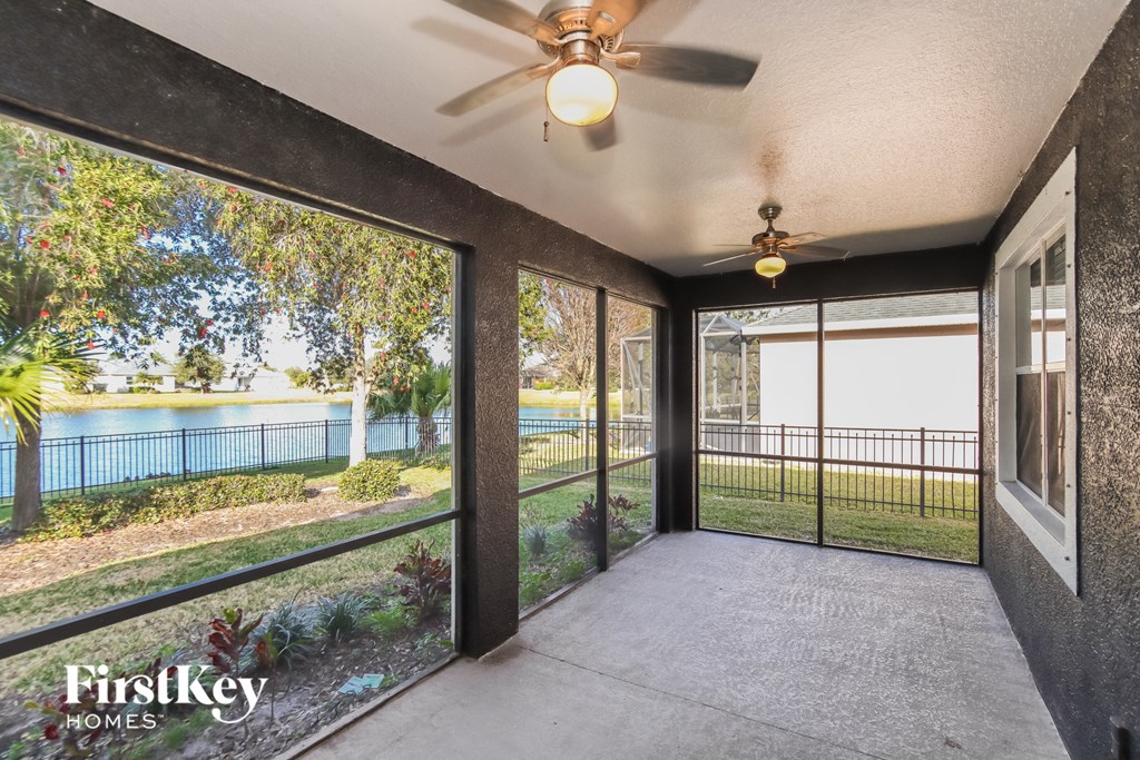 a patio with a view of a lake and a ceiling fan